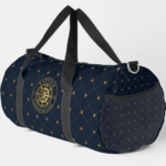 Gold Ship Wheel Duffle Bag Navy blue duffel bag with a quilted design featuring gold stitching, an emblem with the word "CAPTAIN" surrounded by a rope and ship wheel, and a side mesh pocket, with two black shoulder straps.